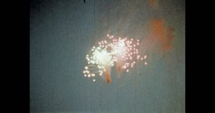 Bright salute, fireworks explosion in blue evening sky. Holiday fireworks lights explode in dark sky background. Celebrate in festival event. Archival vintage color film. Archive video. Old retro