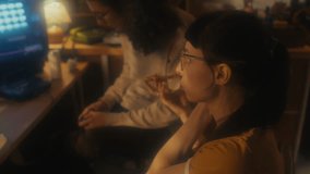 Selective focus shot of young woman eating pizza for lunch while her male co-worker playing console video game in retro office
