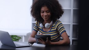 Young African American woman with wearing headphones and laptop at desk in office, Online education, Young African American.