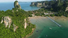 Krabi, Thailand: Aerial drone footage of the dramatic cliff rising above Railay beach in Krabi in southern Thailand by the Andaman sea with a revealing tilt up rotation motion. 
