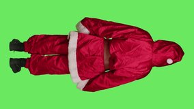Saint nick laughing on camera, posing in red costume over full body greenscreen. Santa cosplay spreading christmas eve holiday spirit, portraying famous winter character with hat and glasses.