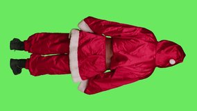 Father christmas in costume standing over full body greenscreen backdrop, posing as main character during winter holidays. Man dressed like santa claus with white beard having fun.