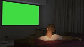 A room with a large green screen. Media. A large spacious room with a green projector.