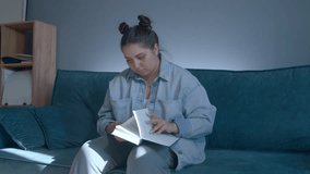 Young student woman reading book, preparing for exams. Media. Girl on sofa at home trying to find information in a book. - Powered by Shutterstock - Get 15% off with code: PIKWIZARD15