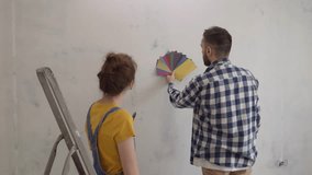 Beautiful happy young family standing against a wall choose color of samples. High quality 4k footage - Powered by Shutterstock - Get 15% off with code: PIKWIZARD15