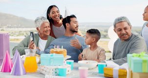 Phone, video call and big family at a party celebration with a dessert cake and presents or gifts. Happy, smile and people on a virtual conversation to celebrate with young man at a birthday event.