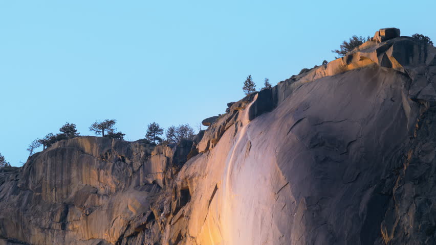 Panning view of wonderful Yosemite Firefall located in Yosemite National Park, California, USA. Breathtaking shot of Horsetail fall, occurs on the east side of El Capitan rock formation, 4k footage