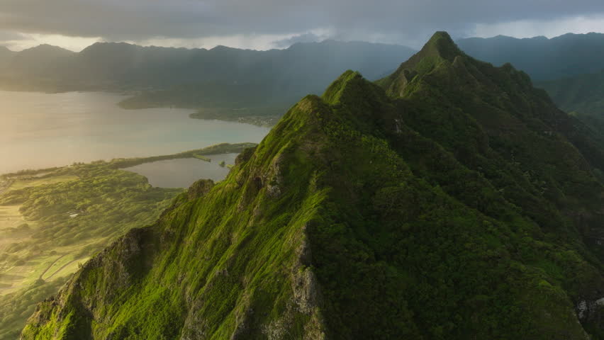 Scenic Oahu coast with beautiful ridges of volcanic mountains. Incredible scenery of green and weird-shaped peaks over ocean coast.Kualoa Ranch 4K. Cinematic Hawaii nature landscapes at golden sunrise