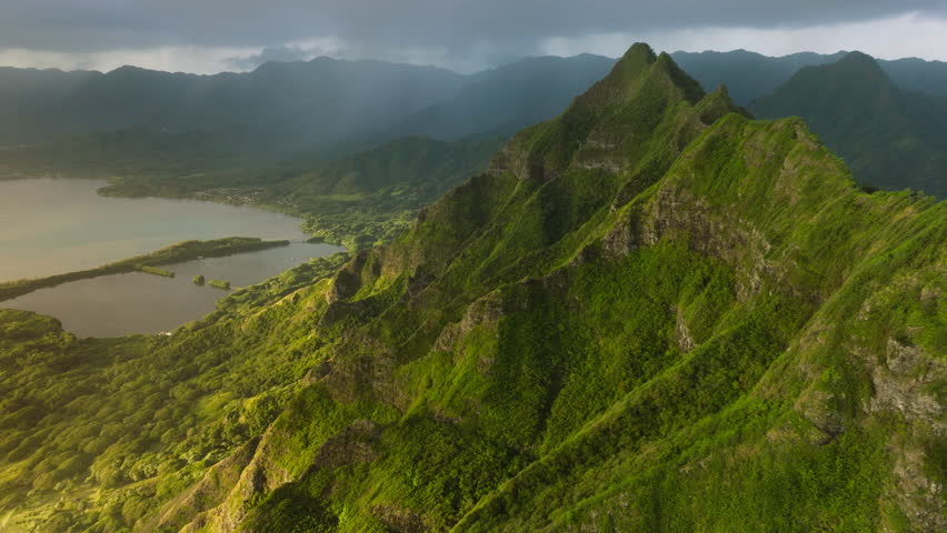 Scenic Oahu coast with beautiful ridges of volcanic mountains. Incredible scenery of green and weird-shaped peaks over ocean coast.Kualoa Ranch 4K. Cinematic Hawaii nature landscapes at golden sunrise