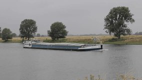 Ship moving by river during gloomy daytime. Netherlands