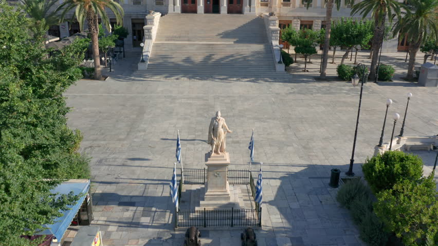 Drone shot of a woman walking towards the city hall of Ermoupoli in Syros, Greece during sunrise