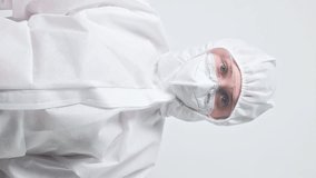 Vertical video. USA medicine. National healthcare system. United states coronavirus. Female doctor woman in protective coverall suit with American flag isolated on grey background.