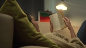 Close-up Happy woman opening, reading and relaxing a book on relax time at home. Vacation time of female reading a book on sofa at night. Education concept. - Powered by Shutterstock - Get 15% off with code: PIKWIZARD15