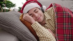 Young hispanic man sleeping on sofa by christmas tree wearing headphones at home - Powered by Shutterstock - Get 15% off with code: PIKWIZARD15
