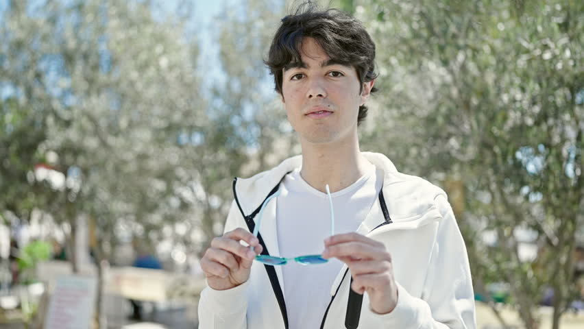 Young hispanic man smiling confident wearing sunglasses at park