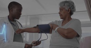 Animation of cardiograph and heart over diverse senior female patient and doctor taking pressure. Medicine, health and digital interface concept, digitally generated video.