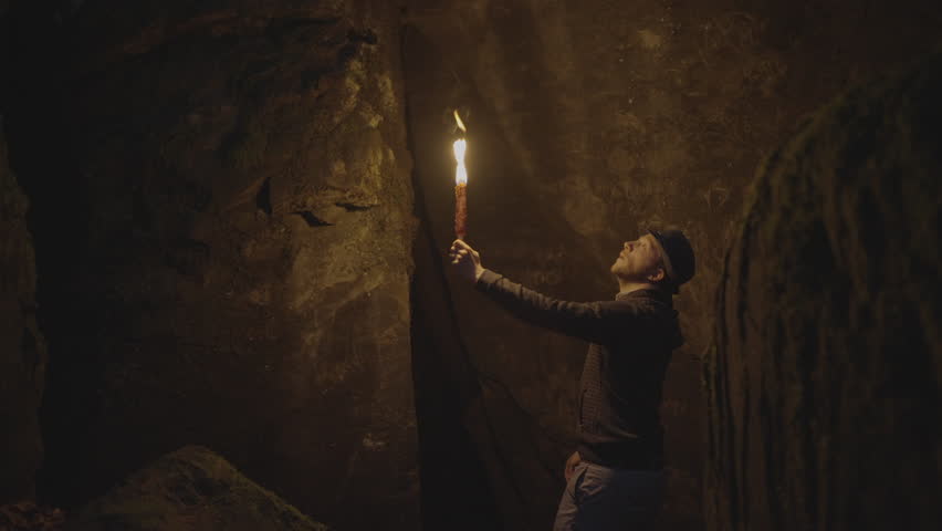 Male Adventurer Exploring Stone Rock Cave in Darkness Outside Using Torch Light Royalty-Free Stock Footage #1106084359
