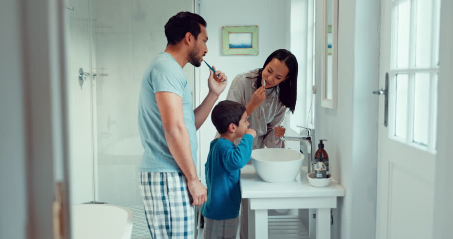 Parents, child and brushing teeth in family home bathroom while learning or teaching dental hygiene. A woman, man and kid with toothbrush and toothpaste for health, cleaning mouth and wellness Royalty-Free Stock Footage #1106085433