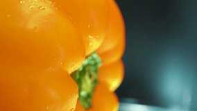 A vertical macro close up shot of a wet sweet yellow pepper on a 360 rotating stand, shiny sweaty water drops, cinematic studio lighting, slow motion, 4k video