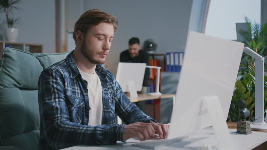 Attractive caucasian male office manager using personal computer typing keyboard solving work tasks and smiling to camera. Coworking space. Freelancer. | Shutterstock HD Video #1106090307