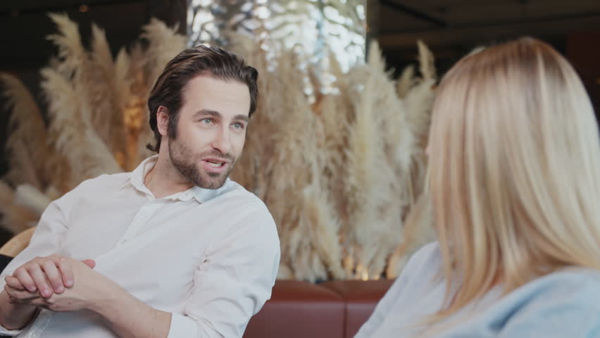 Attractive man and beautiful woman in a cafe. Talking discussing smiling sitting. Modern interior. Have conversations together. Woman and man. Slow motion | Shutterstock HD Video #1106090321