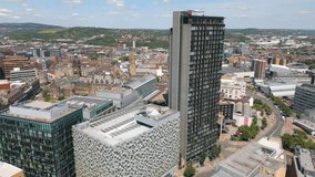 This aerial drone video shows the city centre of Sheffield. There are many office buildings along the skyline of Sheffield in South-Yorkshire, England.