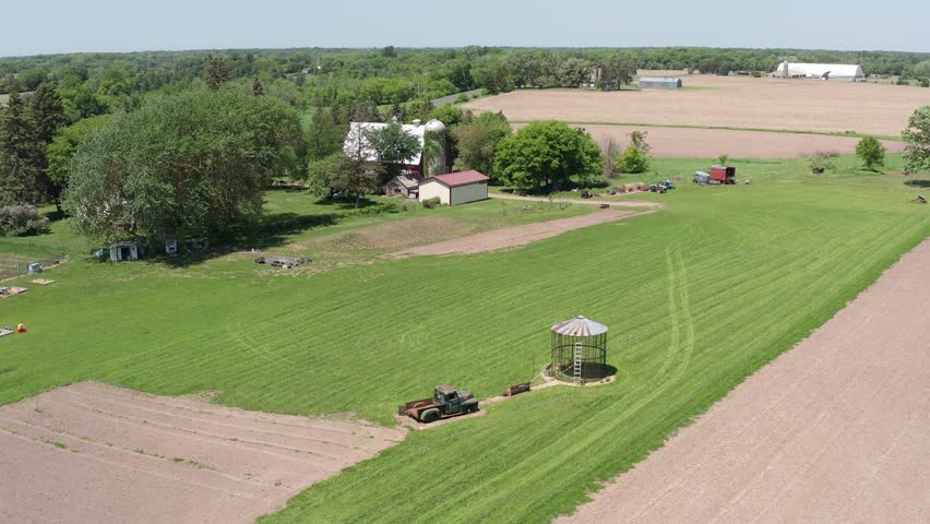 Close-up descending aerial shot of an empty corn silo and old farm truck in the rural fields of Minnesota. 4K