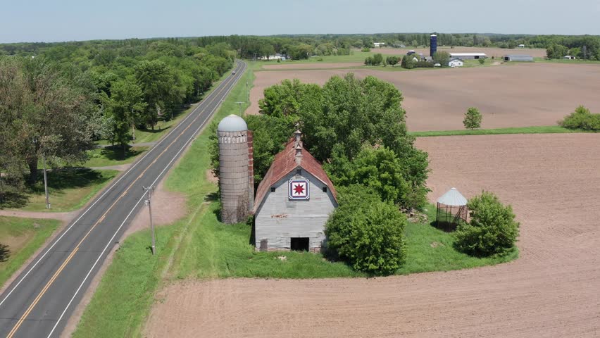 Aerial close-up panning shot of an old barn and silo in the rural farmland of Minnesota. 4K