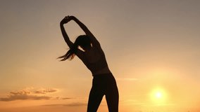 Athletic muscular female sport exercising outdoor workout physical activity at sunset sunrise sun sky horizon. Fitness woman stretching body raising hands pilates exercise at morning evening landscape - Powered by Shutterstock - Get 15% off with code: PIKWIZARD15
