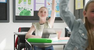 Video of attentive caucasian schoolgirl at desk, raising hand and talking in class, copy space. Education, childhood, elementary school and learning concept.