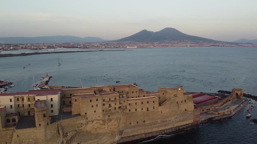 Camera truck leftward over Naples, overlooking the Vesuvio Vulcan, the the Ovo Castle on the foreground, late sunset time - 60fp - 2k