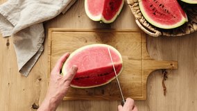 Watermelon slices. A person slicing watermelon on the wooden cutting board on the table. Stock video 4k