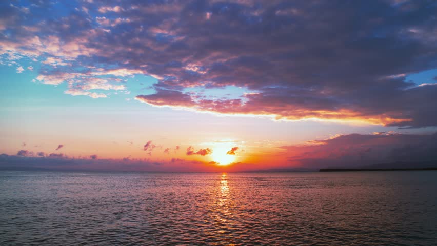 Sunset over the Mediterranean Sea on a tropical summer evening. Sea waves with sunset reflections. Ripples of water with sunbeams. Deep blue ocean under an orange sky. Twilight over the sea.
