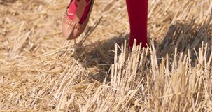Bulgarian girl in traditional ethnic folklore leather shoes walking on a harvested wheat field