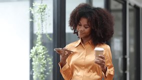Happy young African American woman using a smart phone in office.