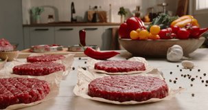 Hamburger blanks on parchment paper hamburger molds, subdued light, kitchen, table, vegetable bowl, minced meat bowl, spices, black pepper, rosemary, hot pepper. Advertising. Healthy clean eating