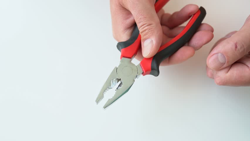 Close up of the person hand holding and squeeze universal or combination pliers. Man hold and squeezing and unclenching work tool going something repair or construction to do or some kind. 4K 25FPS Royalty-Free Stock Footage #1106126711