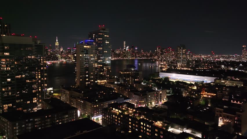 Warm-lit Williamsburg tower rises above waterfront streets, 2023.