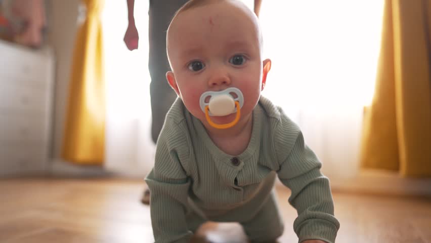 Cute baby with joyful expression, laughing, crawling on floor from his father who is chasing him. child crawls on wooden parquet and looks with happy face. Happy laughing baby crawling with father. Royalty-Free Stock Footage #1106132329