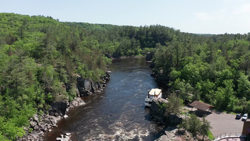 Aerial descending and panning shot of a riverboat docked on the Saint Croix River in Taylors Falls, Minnesota. 4K