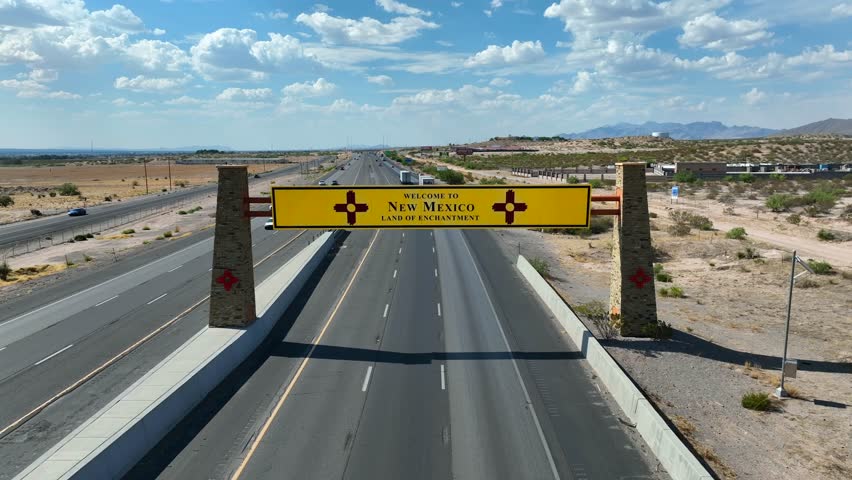 New Mexico welcome sign above highway. Aerial dolly forward towards establishing sign of NM.