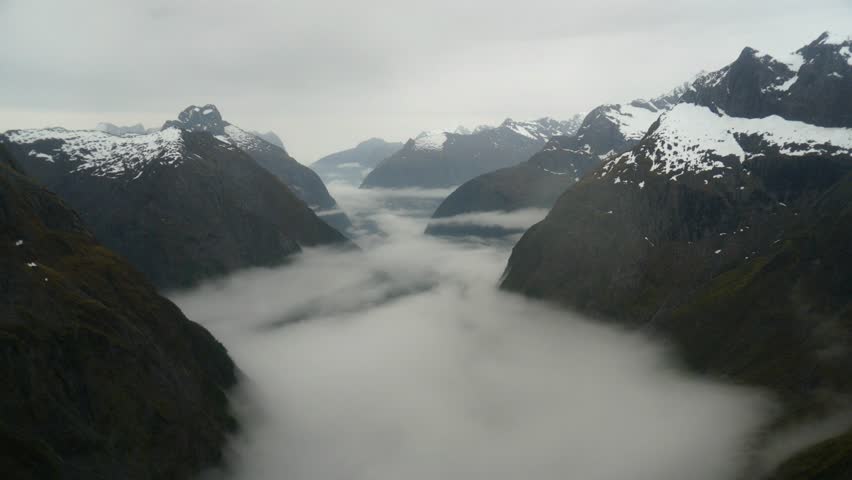 Timelapse shot capturing pristine landscape of Gertrude Saddle on Fiordland National Park with misty cloud forming between the rocky valley on a cold rainy day during winter season. Royalty-Free Stock Footage #1106134803
