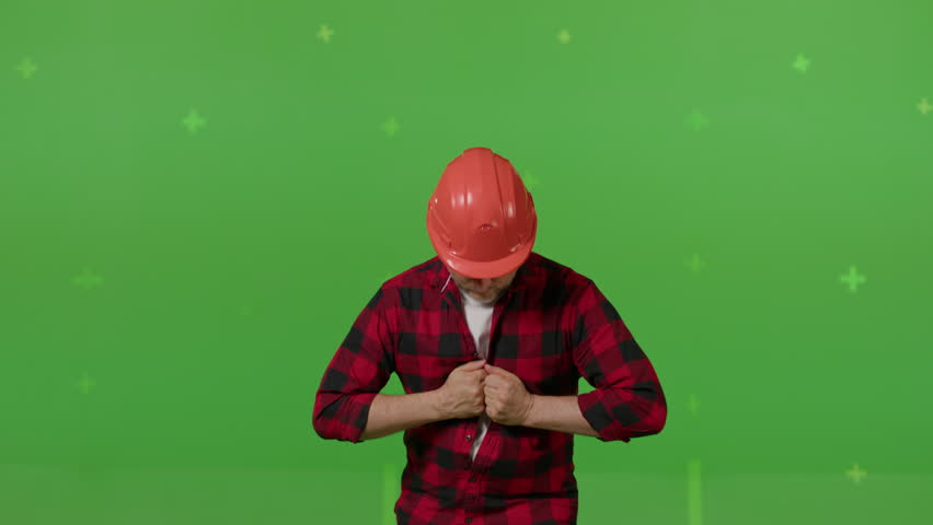Joyful construction worker turning spreading shirt and showing white t-shirt on green background