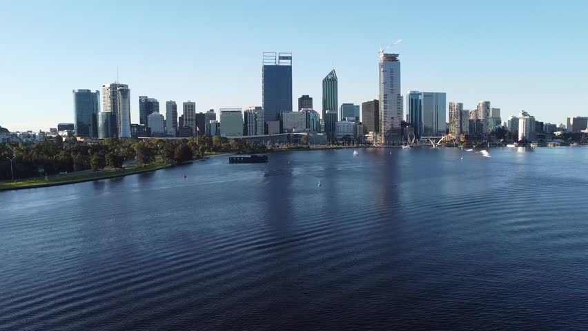 Drone shot descending down to sanding beach bank of Swan River with skyline of Perth, Western Australia from and South Perth foreshore