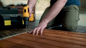 Close-up view of a man drilling holes in a woden panel with a power drill outdoors. Slow motion. - Powered by Shutterstock - Get 15% off with code: PIKWIZARD15