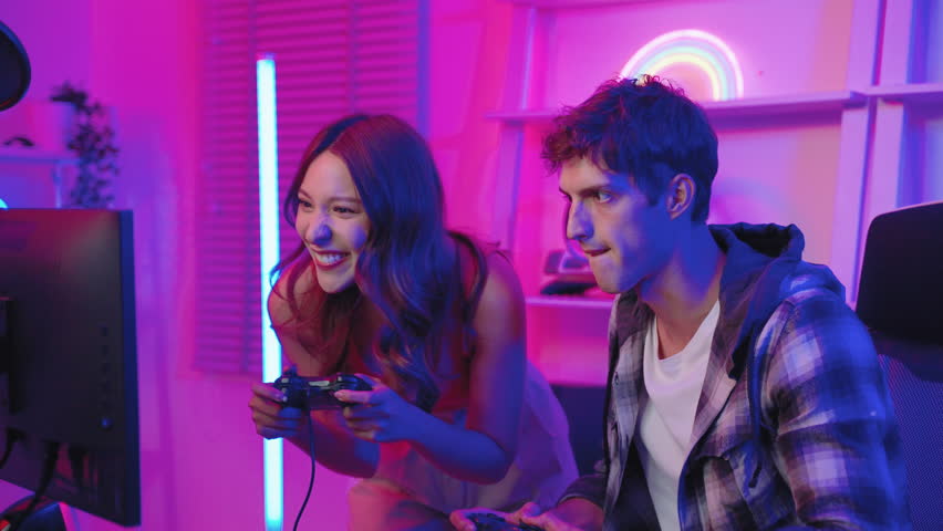 Influencer gamer couple playing games with joystick live streaming on social media in exciting neon atmosphere , technology concept, recreation