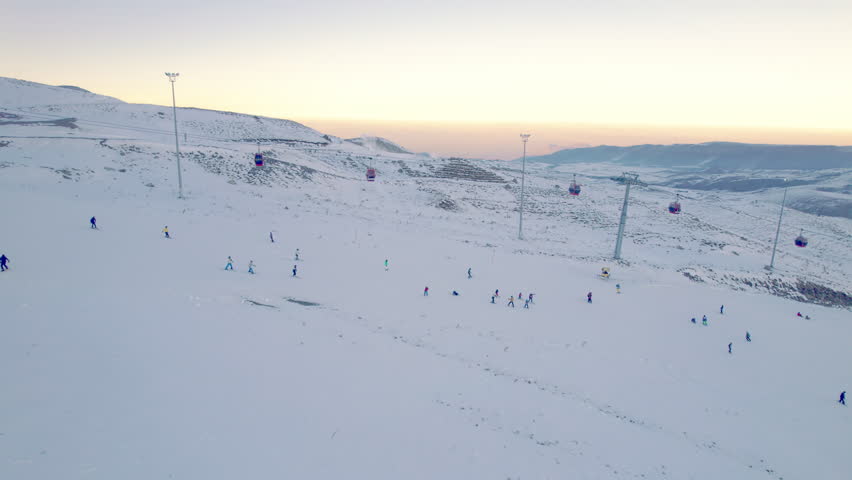 Gondola type cable car and skiers on snow covered slope of ski resort. Landscape with snowy ski piste and skiers. Aerial view. Erciyes Mount, Kayseri province, Turkey