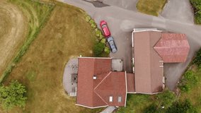 Drone video of a house with red and blue car outside