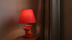 The red table lamp in the apartment turns on and off. Looped endless video.