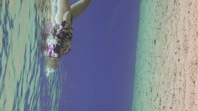 Vertical video, Girl free diver swimming in blue water under surface, Slow motion